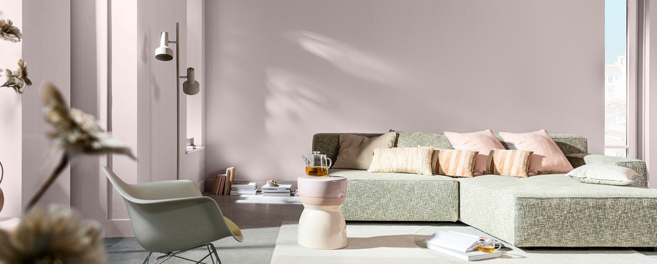 Svetainė su švelniai rožinėmis sienomis ir pilka sofa